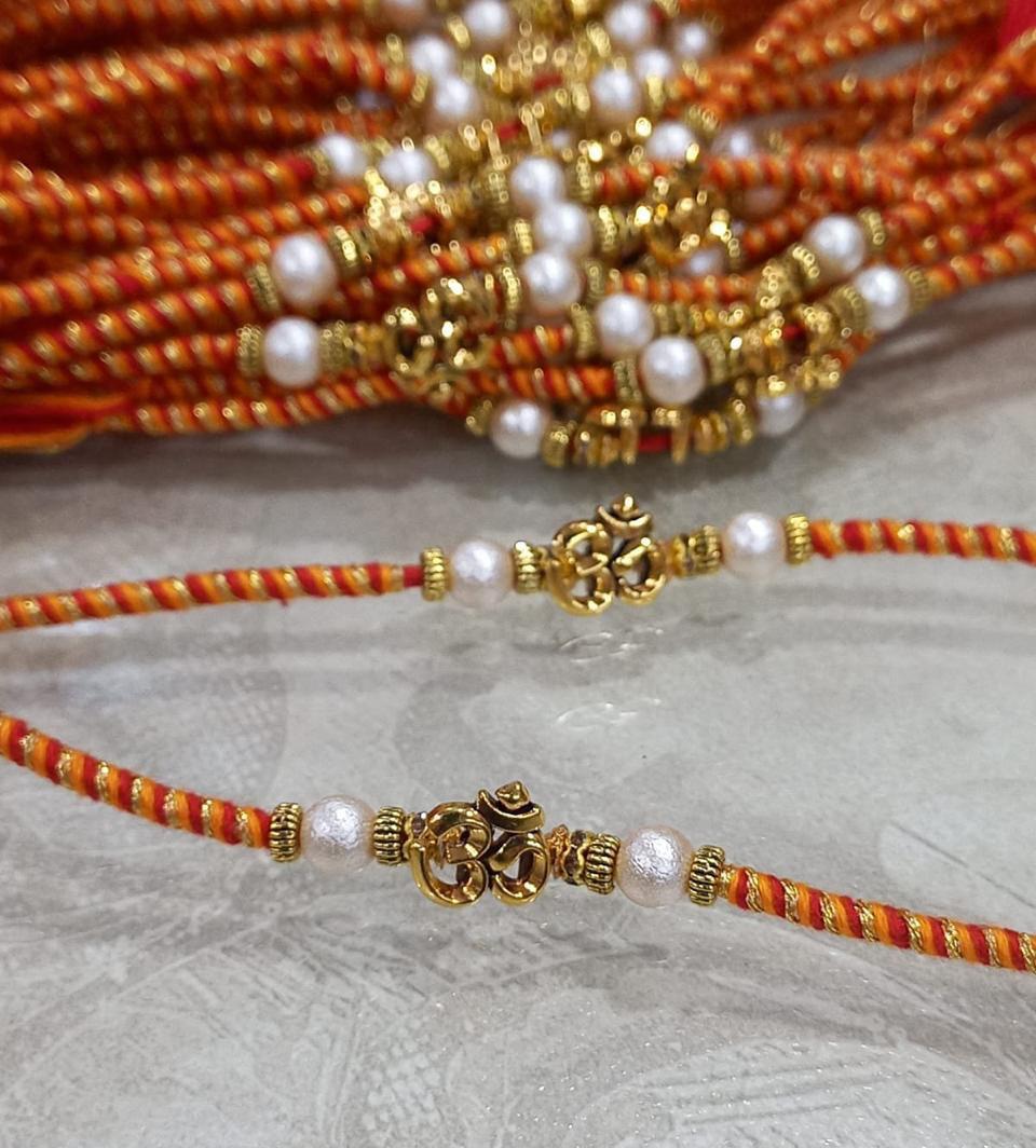 Traditional Om Rakhi with pearl beads and red yellow sacred thread for Raksha Bandhan